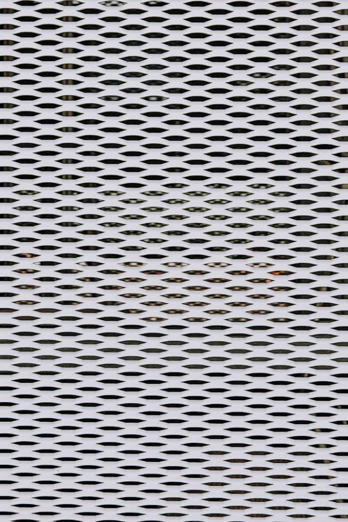 Textured surface of metal fence with holes
